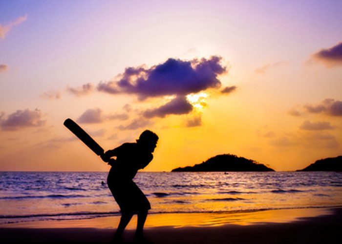 silhouetted cricket player on beach