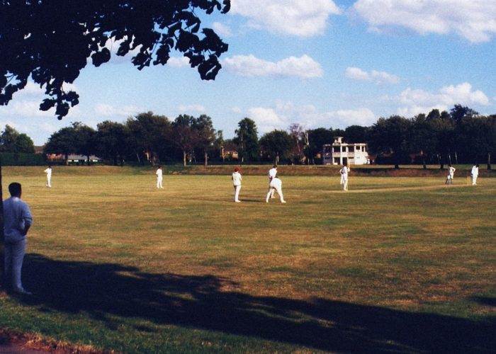 A scene of village cricketers playing. The weather is sunny.