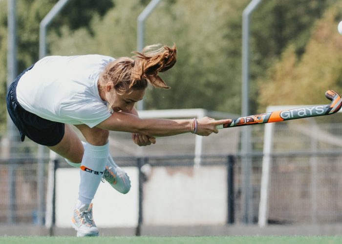 Woman hockey player hitting hockey ball on hockey pitch